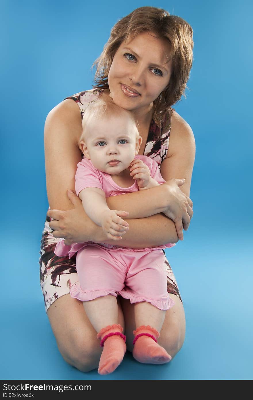 Young and beautiful mother with her sweet little daughter isolated on blue. Young and beautiful mother with her sweet little daughter isolated on blue.