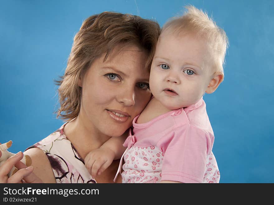 Young and beautiful mother with her sweet little daughter isolated on blue. Young and beautiful mother with her sweet little daughter isolated on blue.