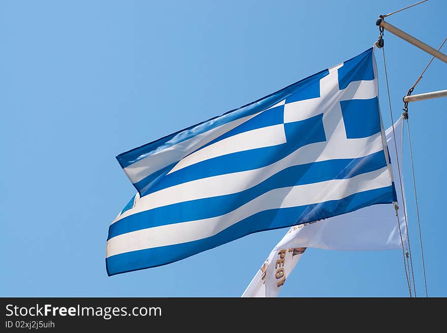 The greek flag waving from the top of a boat