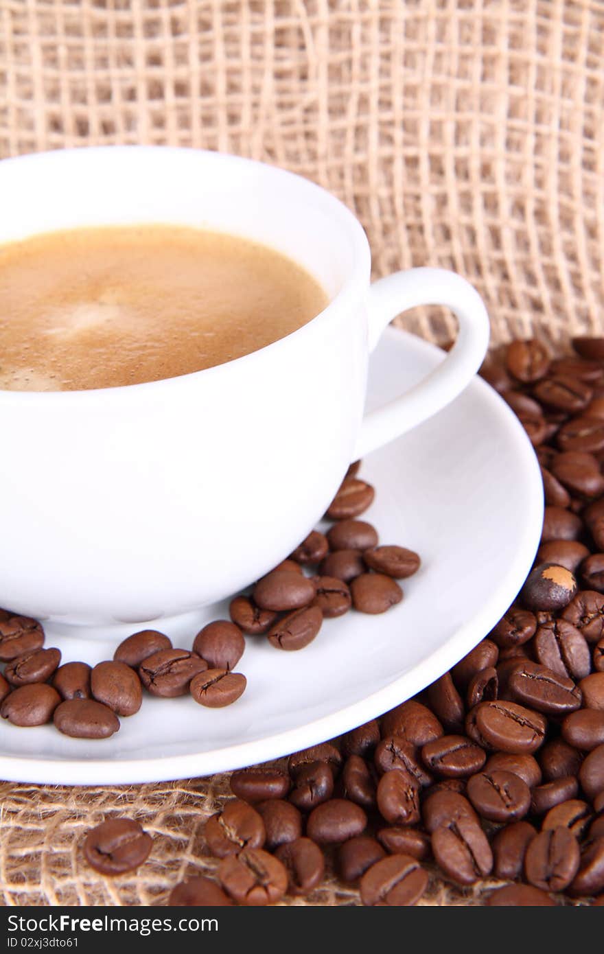 Cup of coffee and coffee beans on burlap material