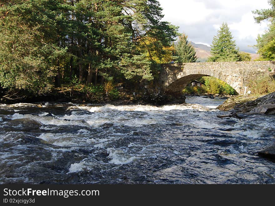 An old stone bridge spans the river dochart over the falls near Killin. An old stone bridge spans the river dochart over the falls near Killin