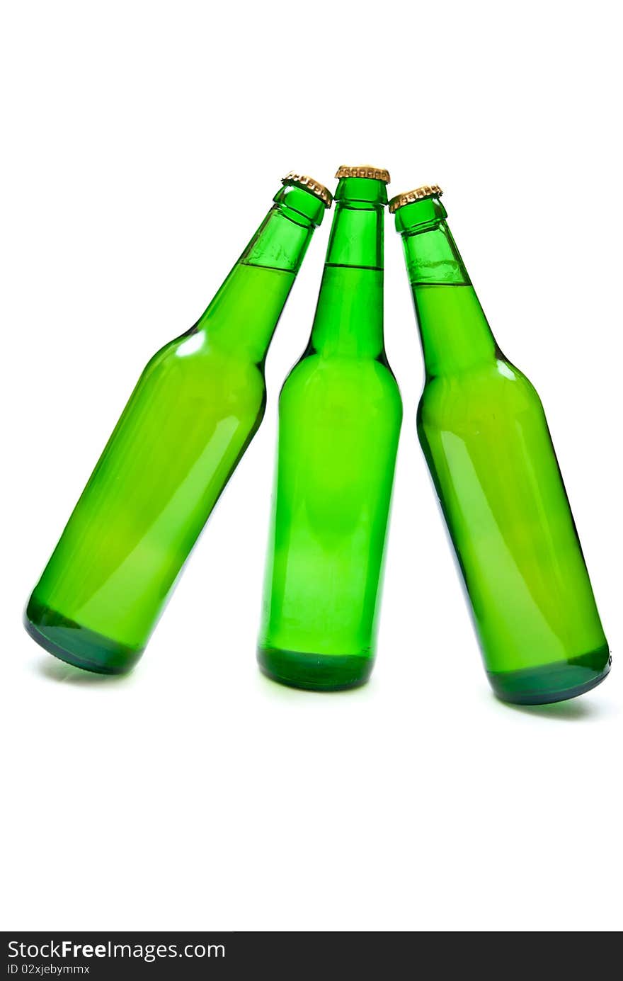 Three cold beers in green bottles isolated on white. Soft shadow. Three cold beers in green bottles isolated on white. Soft shadow