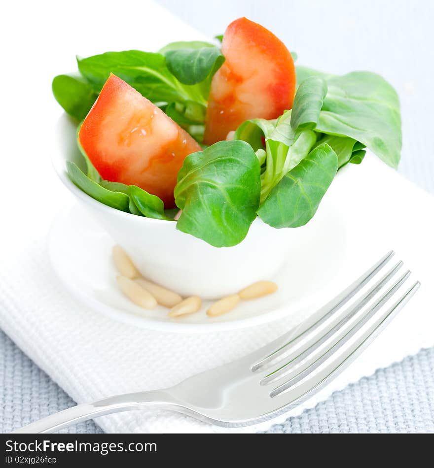 Lambs lettuce in bowl with tomato and pine nuts. Lambs lettuce in bowl with tomato and pine nuts