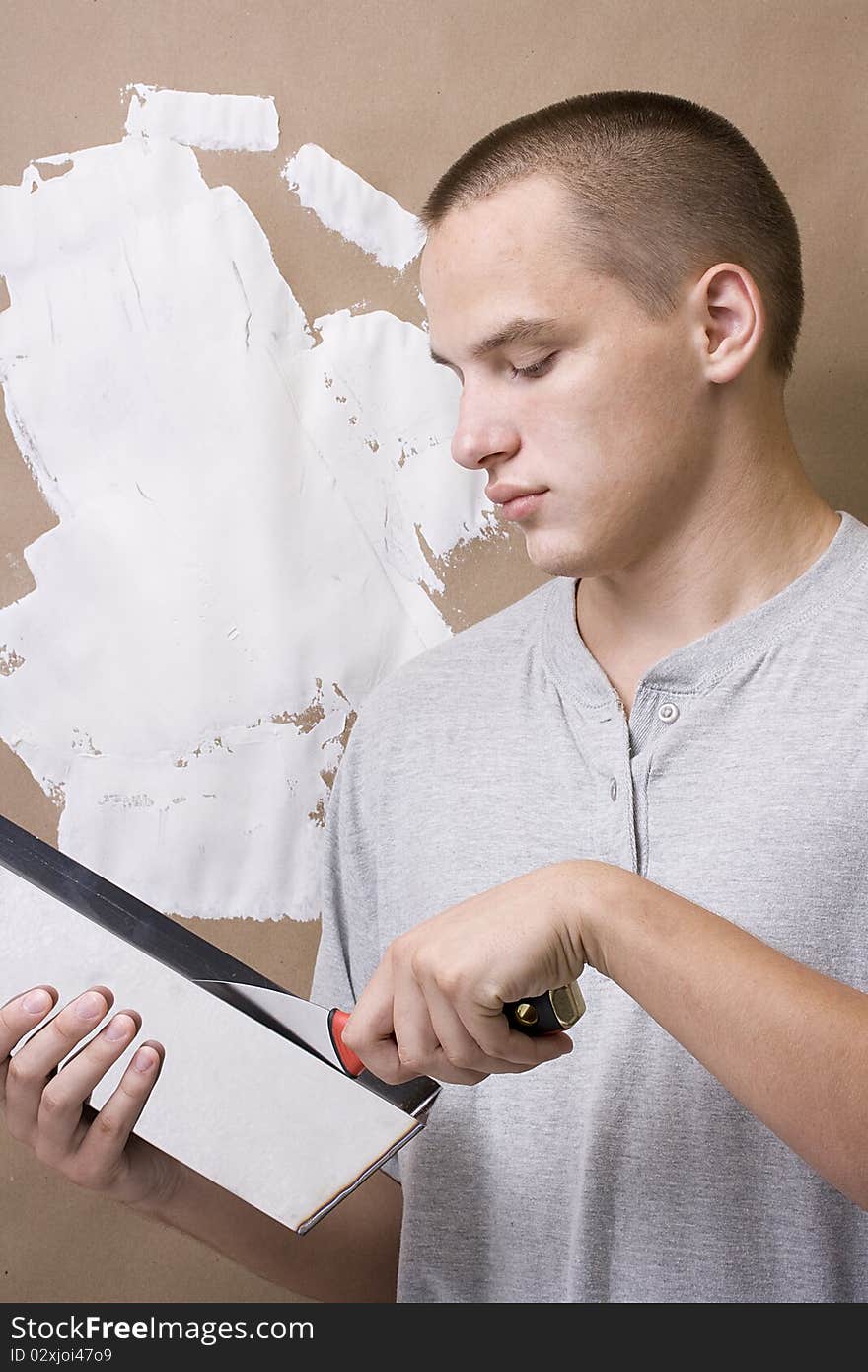 Caucasian man plastering a brown wall with white plaster. Caucasian man plastering a brown wall with white plaster.