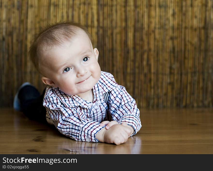 The small cheerful kid lie on a floor. The small cheerful kid lie on a floor.