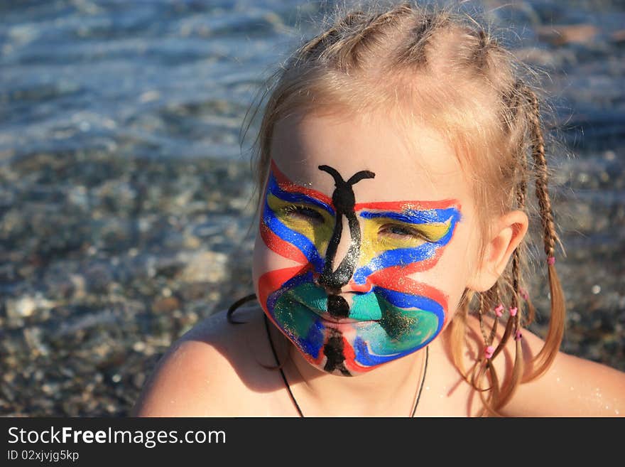 Child's face painted as butterfly at the seaside