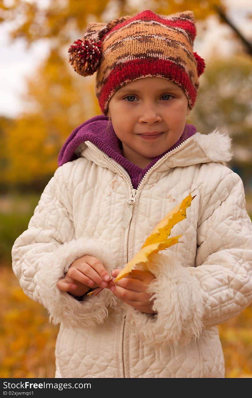 Girl in cute hat with a heap of maple leaves close up against autumn nature. Girl in cute hat with a heap of maple leaves close up against autumn nature