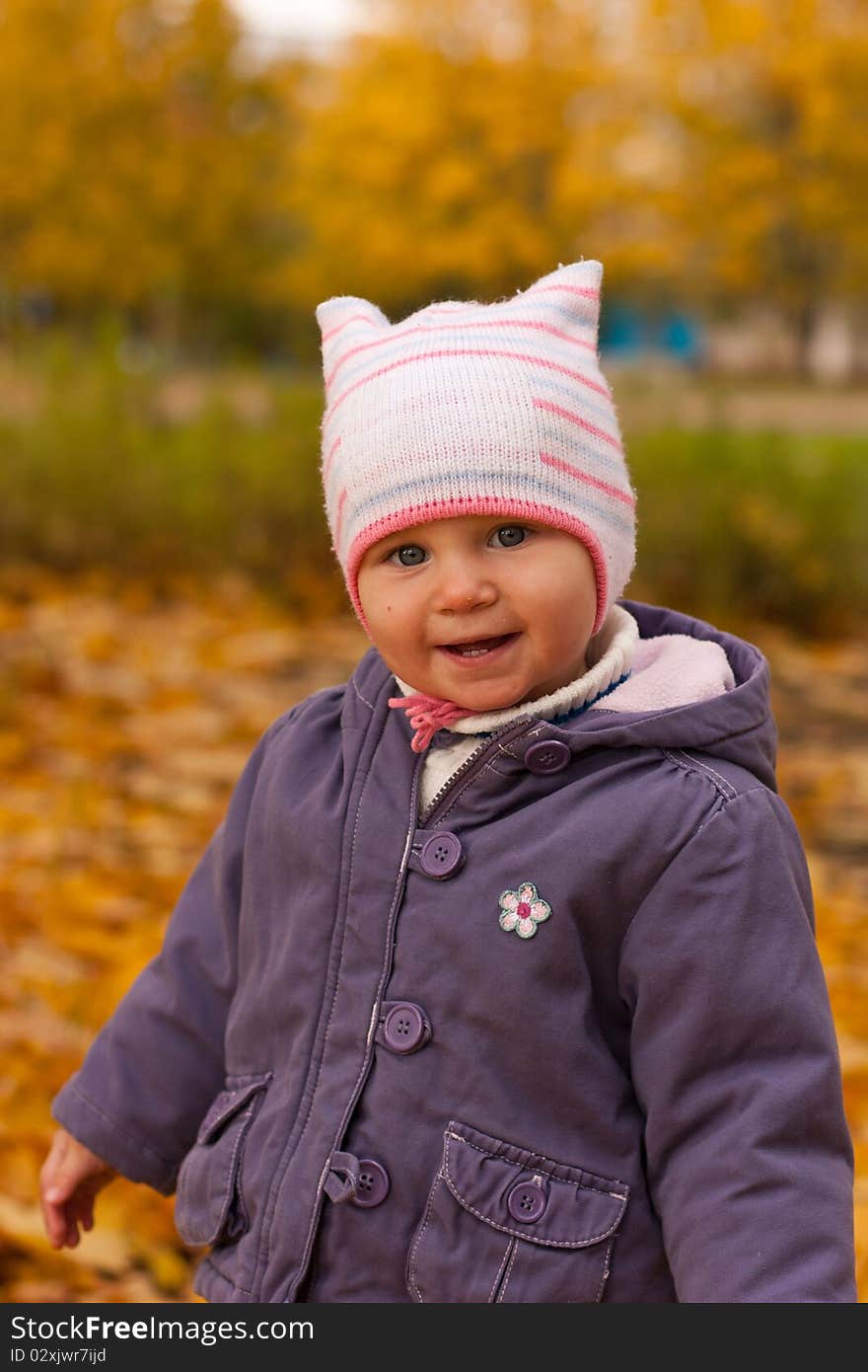 Baby girl in cute hat close up against autumn nature. Baby girl in cute hat close up against autumn nature