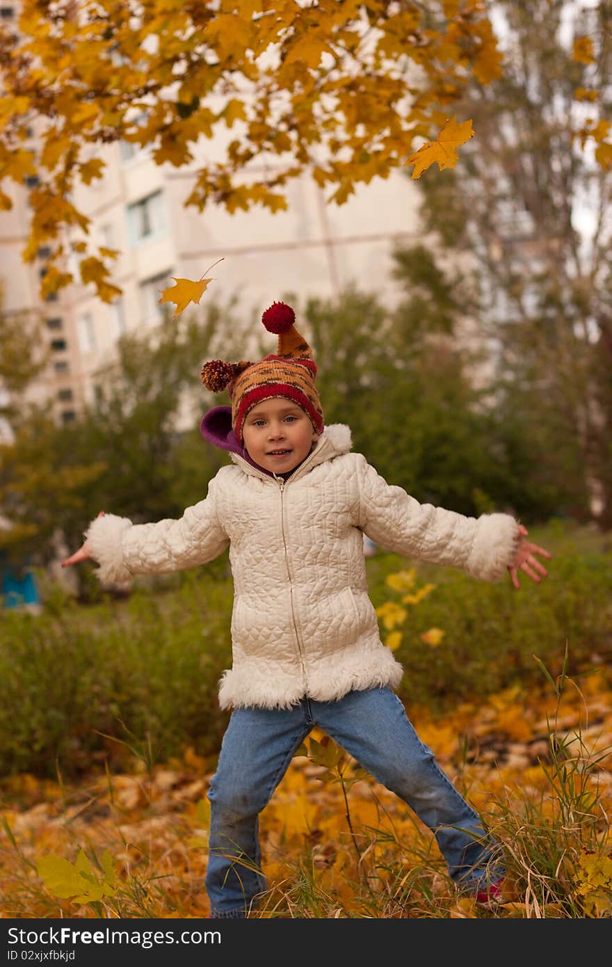 Beautiful girl in funny hat jumping with maple leaves against autumn nature. Beautiful girl in funny hat jumping with maple leaves against autumn nature