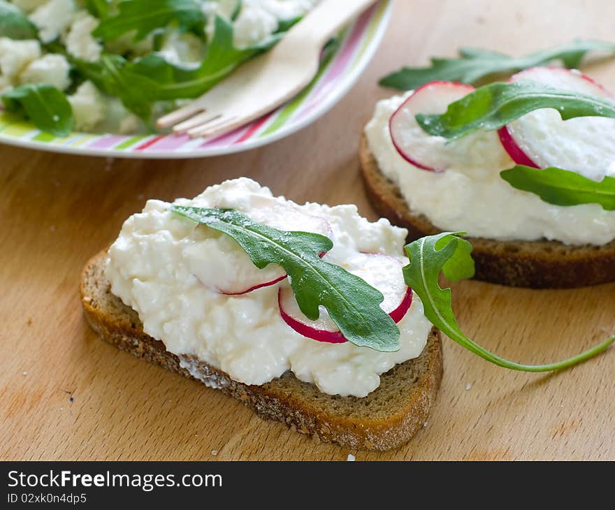 Two bread with cottage cheese, radish and arugula for breakfast