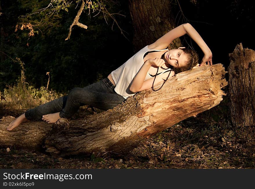 Young girl in jeans and a white T-shirt lying on a fallen tree in  forest. Young girl in jeans and a white T-shirt lying on a fallen tree in  forest