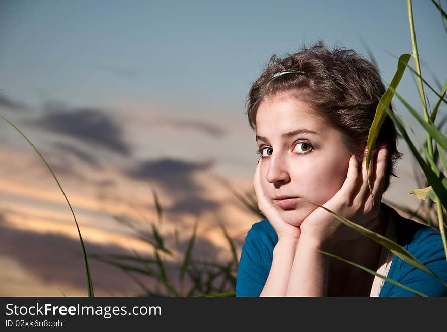 Portrait of a young woman with short hair on against sunset sky