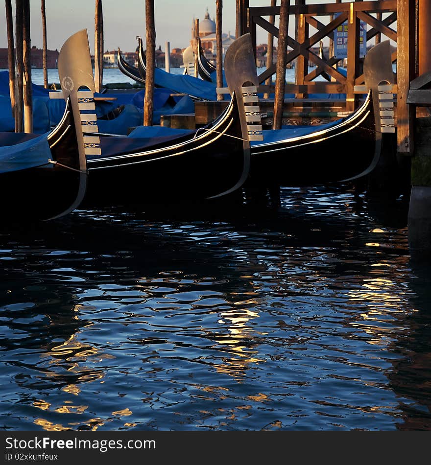 Noses of three gondolas in the dock of Venice. Bright reflections if water.