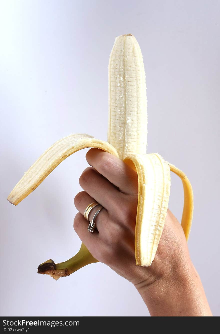 Peeled banana held in the hand by a woman