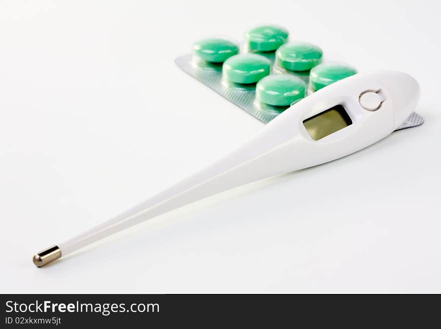 Electronic medical thermometer and pills closeup