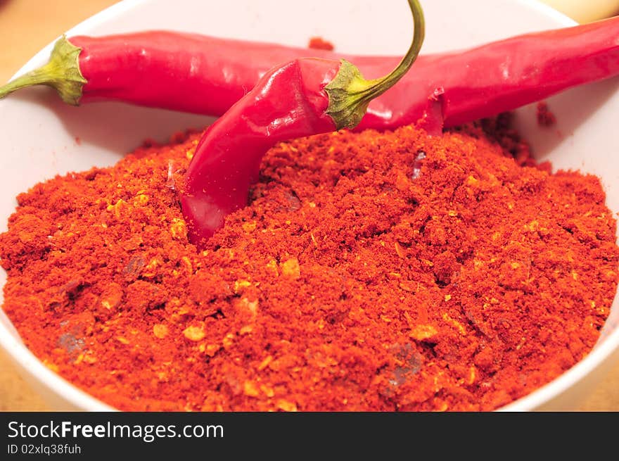 Ground cayenne pepper in porcelain bowl and two dry hot red peppers. Ground cayenne pepper in porcelain bowl and two dry hot red peppers