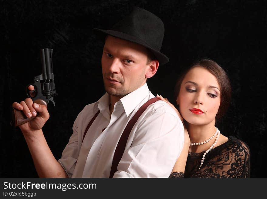 Portrait of the man in a hat with a pistol and the beautiful woman. In style of a retro.