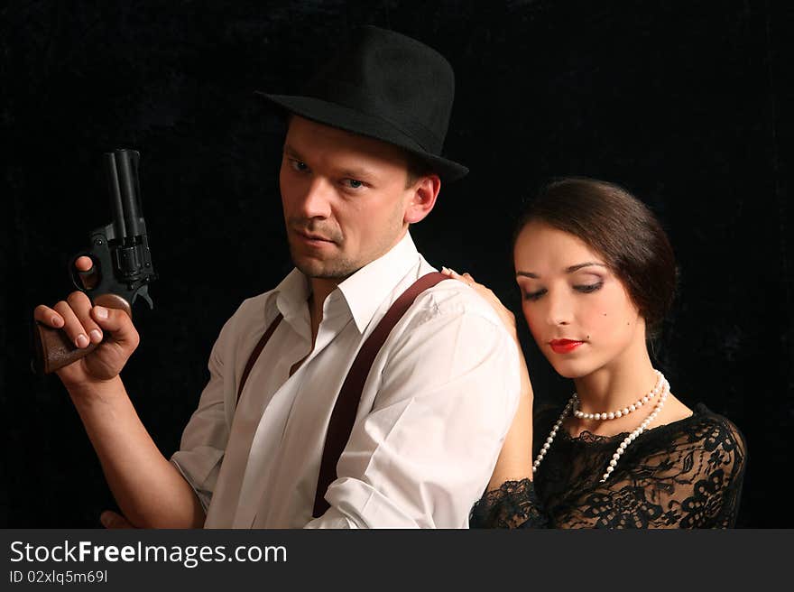 Portrait of the man in a hat with a pistol and the beautiful woman. In style of a retro.