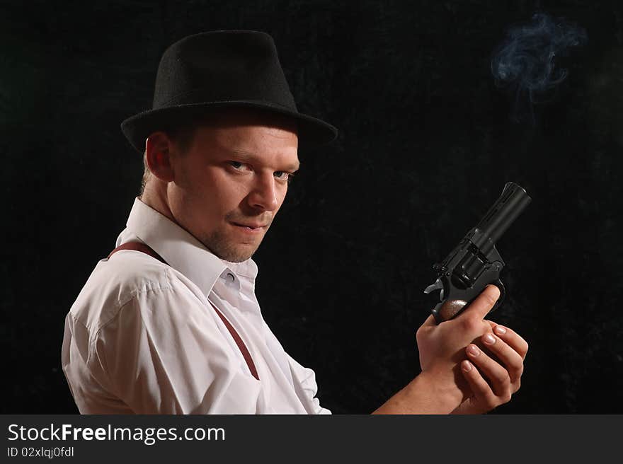 The aggressive man-gangster with a pistol. A portrait on a black background.