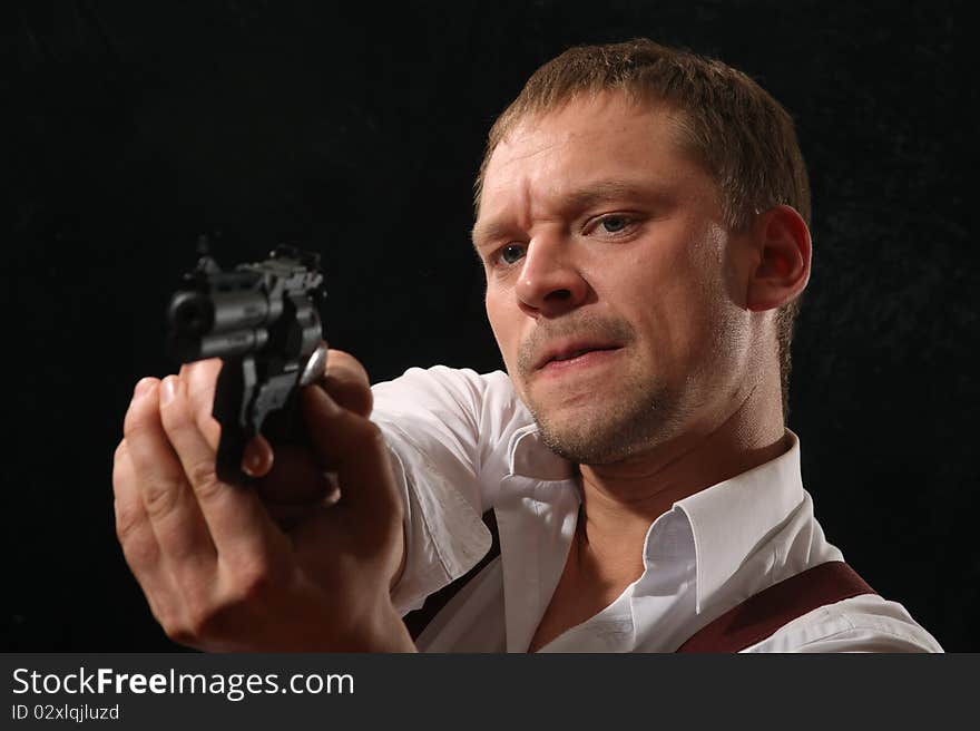 The aggressive man-gangster with a pistol. A portrait on a black background.