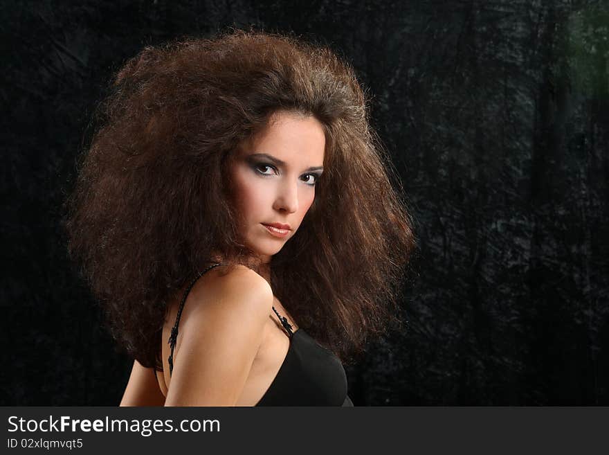 Portrait of the beautiful young woman with a magnificent hairdress on a black background.