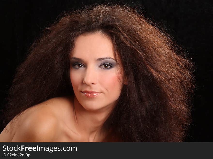 Portrait of the beautiful young woman with a magnificent hairdress on a black background.