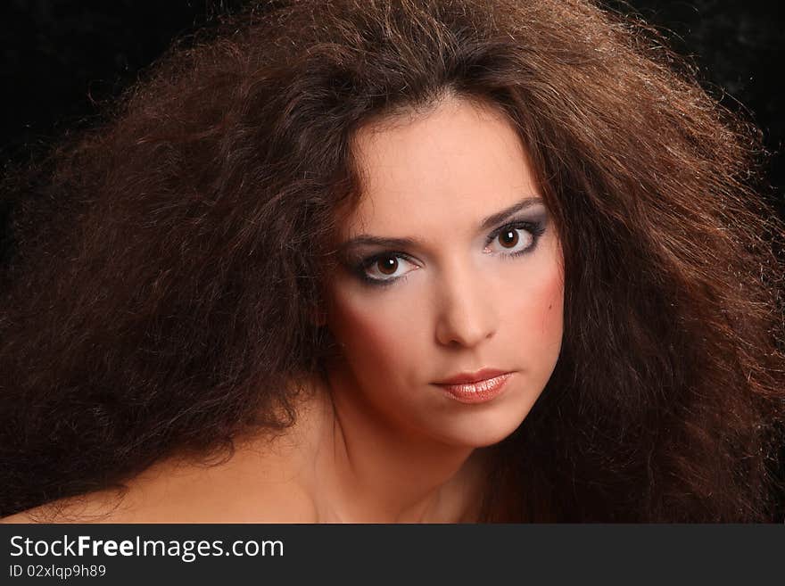 Portrait of the beautiful young woman with a magnificent hairdress on a black background.