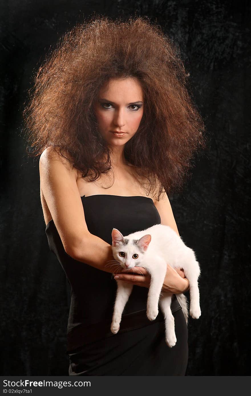 Portrait of the beautiful young woman with a magnificent hairdress And the WHITE CAT ON the SHOULDER on a black background.