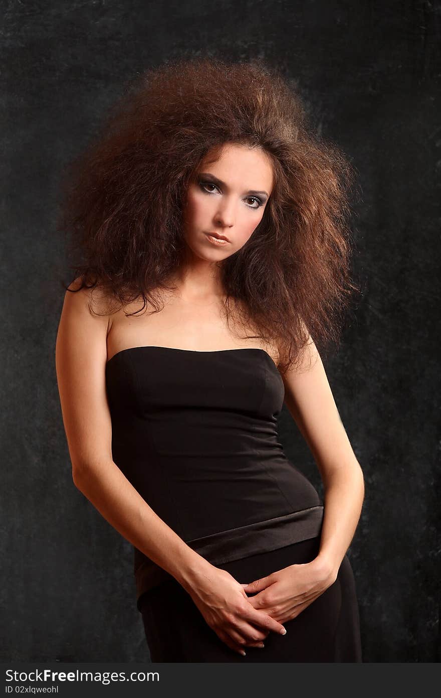 Portrait of the beautiful young woman with a magnificent hairdress on a black background.