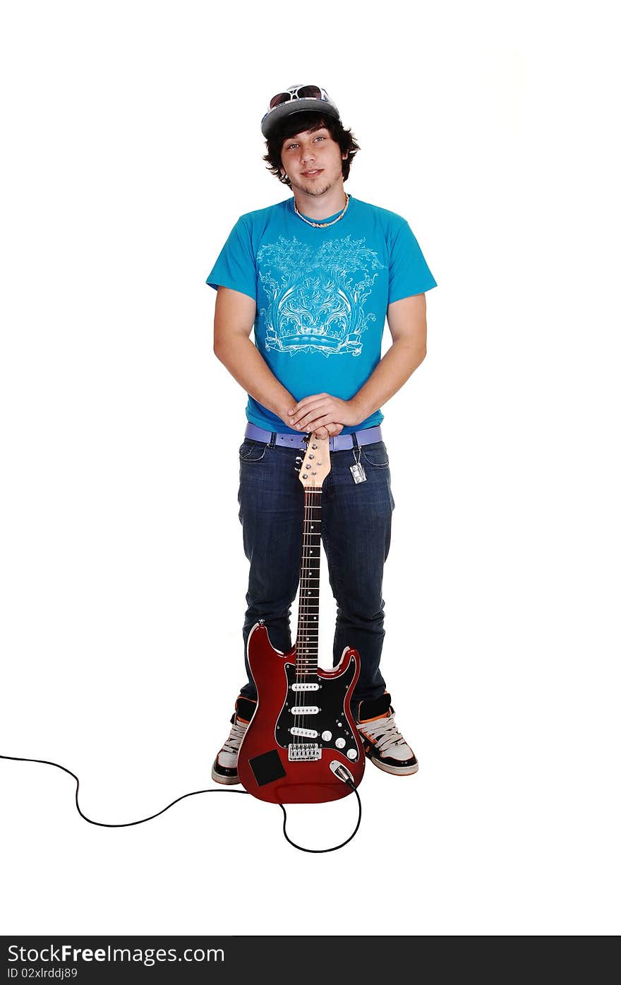 A teenage boy standing in the studio, holding his guitar in jeans and a blue sweater, after playing, for white background. A teenage boy standing in the studio, holding his guitar in jeans and a blue sweater, after playing, for white background.