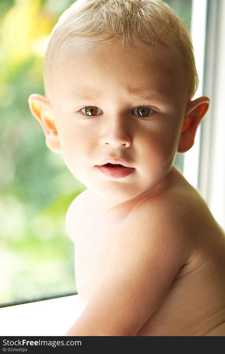 Amusing little boy near the sunny window