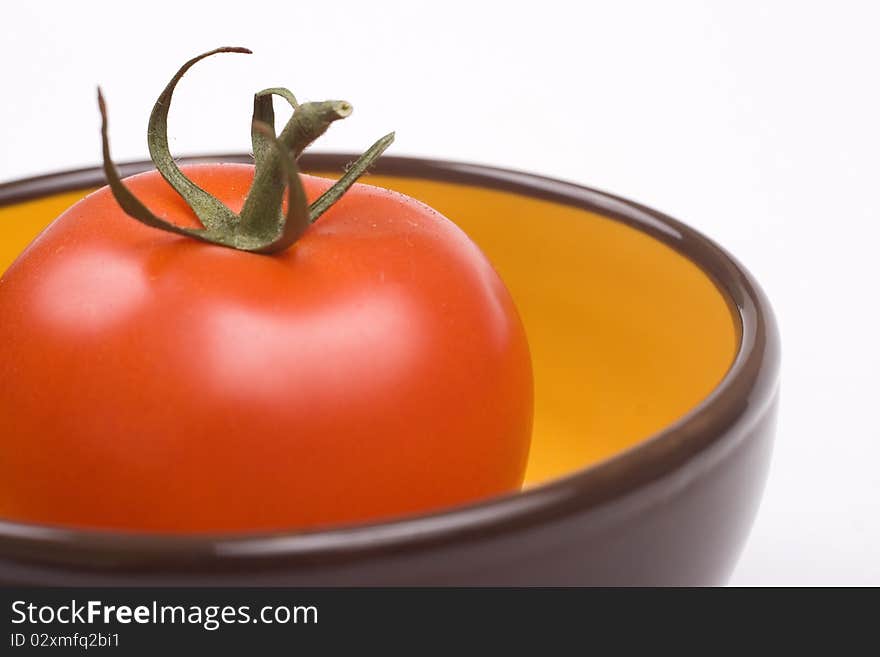 One tomato in a yellow with brown jar. One tomato in a yellow with brown jar