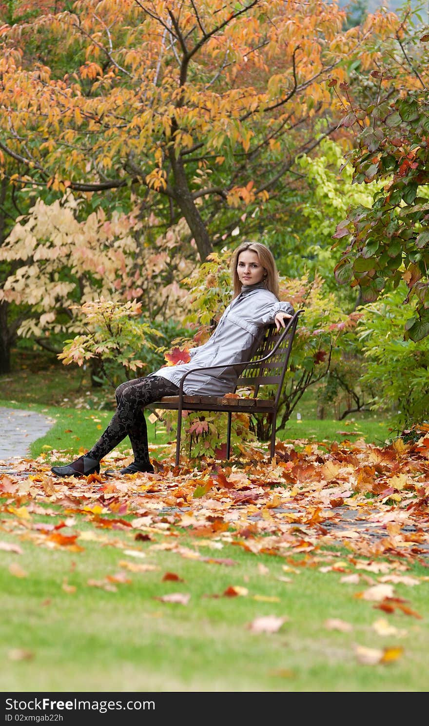 Girl on small bench in autumn park