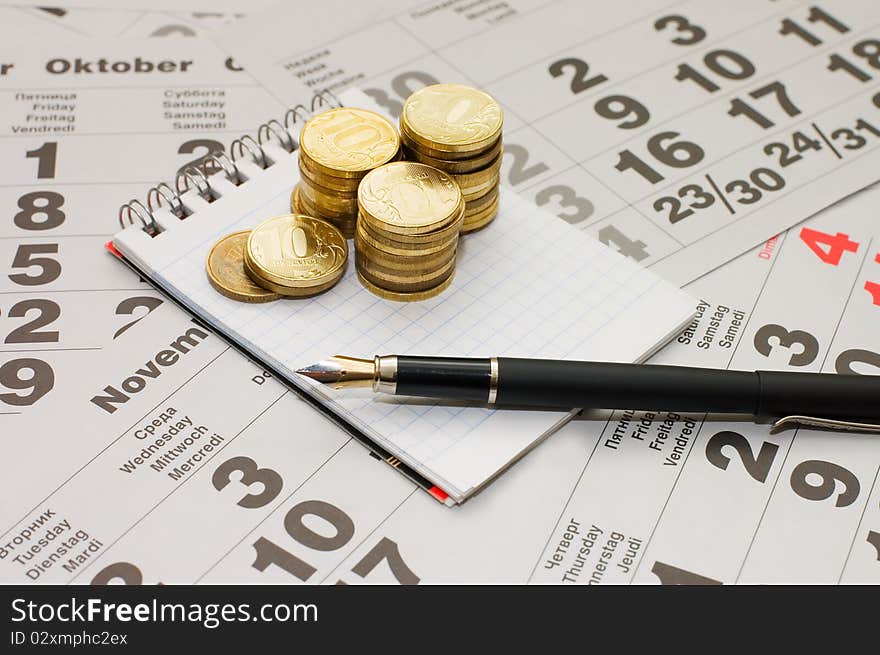 Sheets of a calendar with coins and a notebook