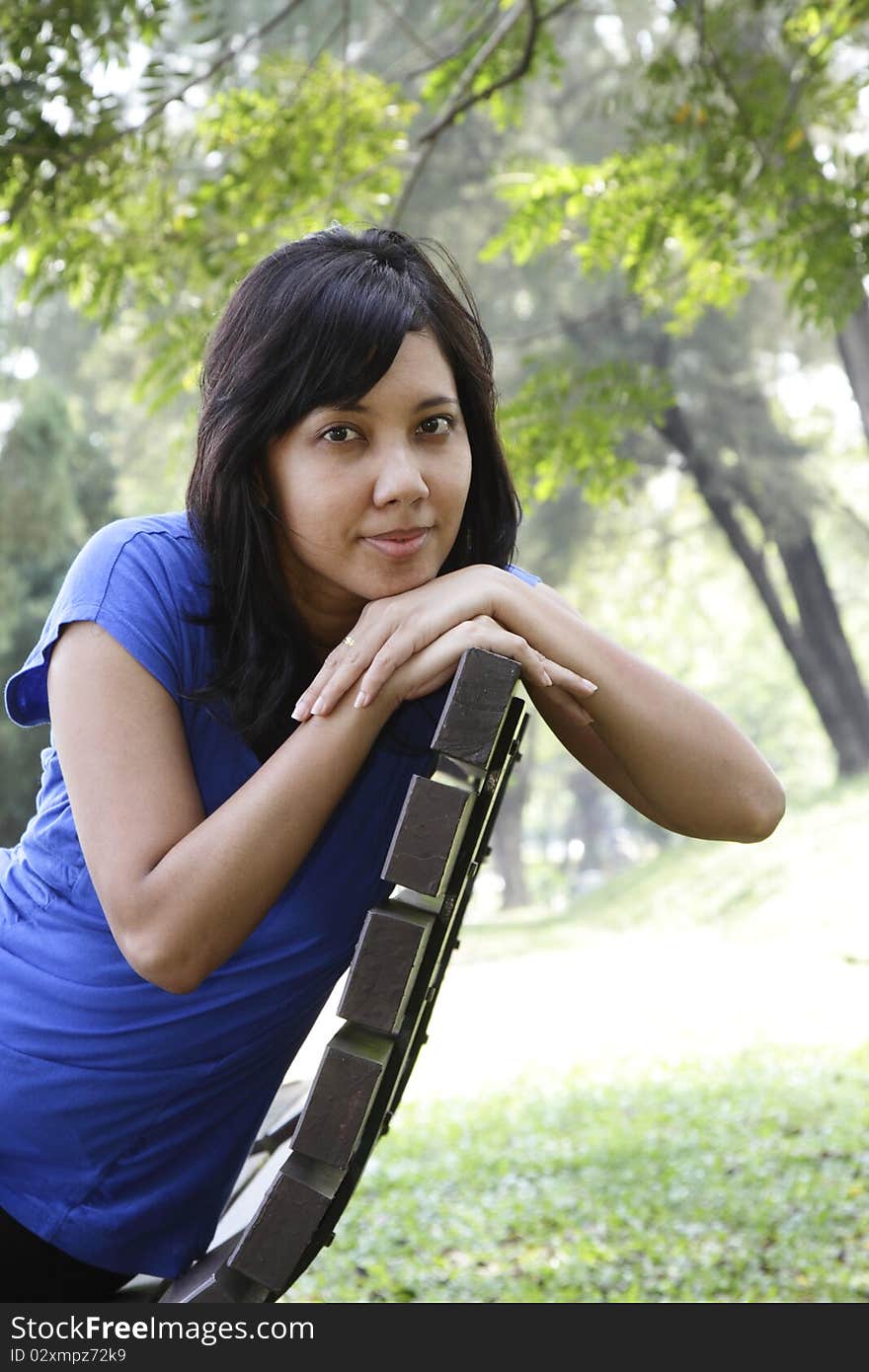 An Asian woman sitting on a park bench. An Asian woman sitting on a park bench