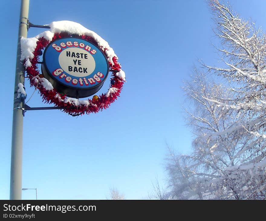 A Street Sign in Scotland at Christmas time. Covered in snow, it reads: Haste ye back. A Street Sign in Scotland at Christmas time. Covered in snow, it reads: Haste ye back.