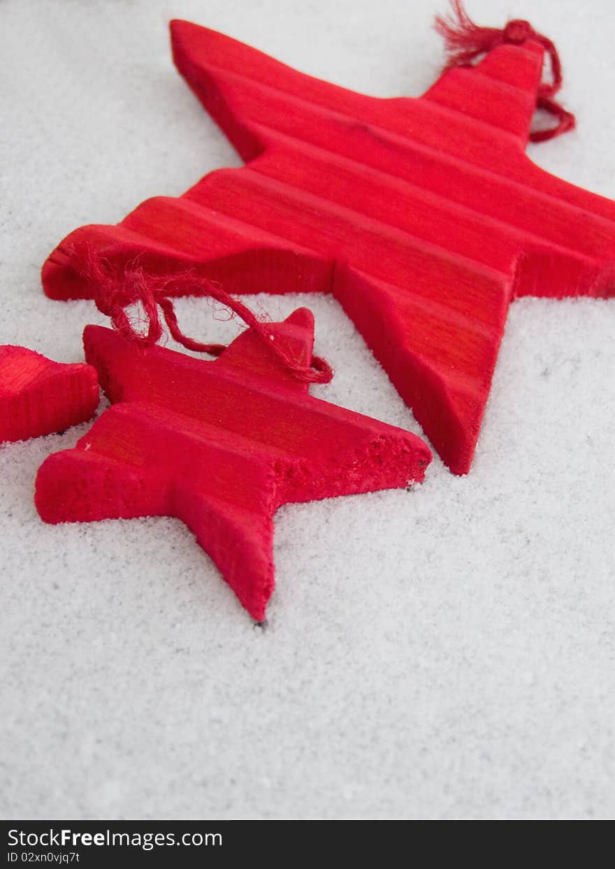 Christmas time concept: wooden red Christmas star decorations in different sizes, laying on the snowy background (isolated) *RAW format available at request. Christmas time concept: wooden red Christmas star decorations in different sizes, laying on the snowy background (isolated) *RAW format available at request