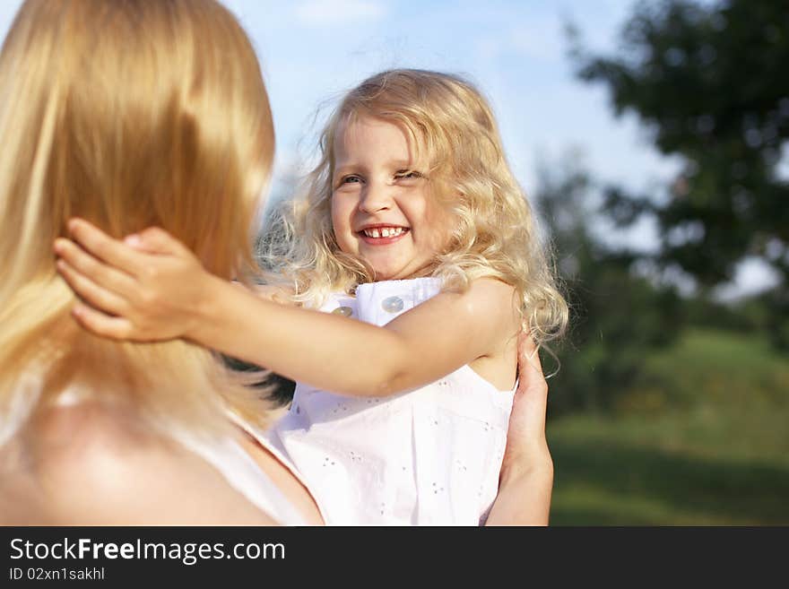 Laughing little girl in mother arms outdoor