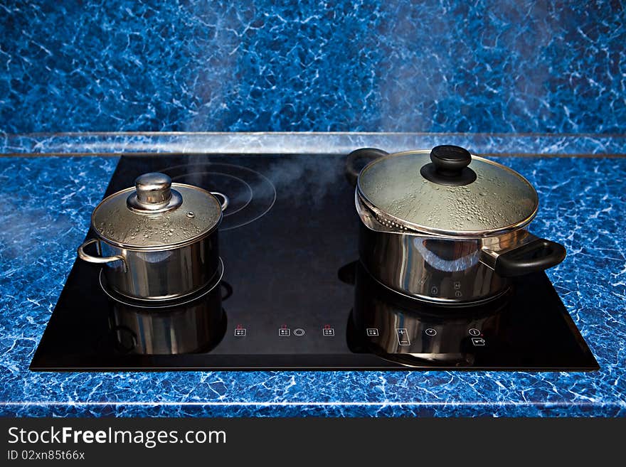 Two metal pans boil on a stove