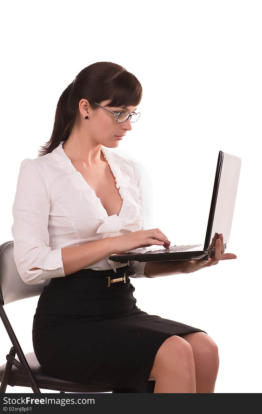 Beautiful business woman with dark hair wearing glasses is sitting with a laptop. Beautiful business woman with dark hair wearing glasses is sitting with a laptop