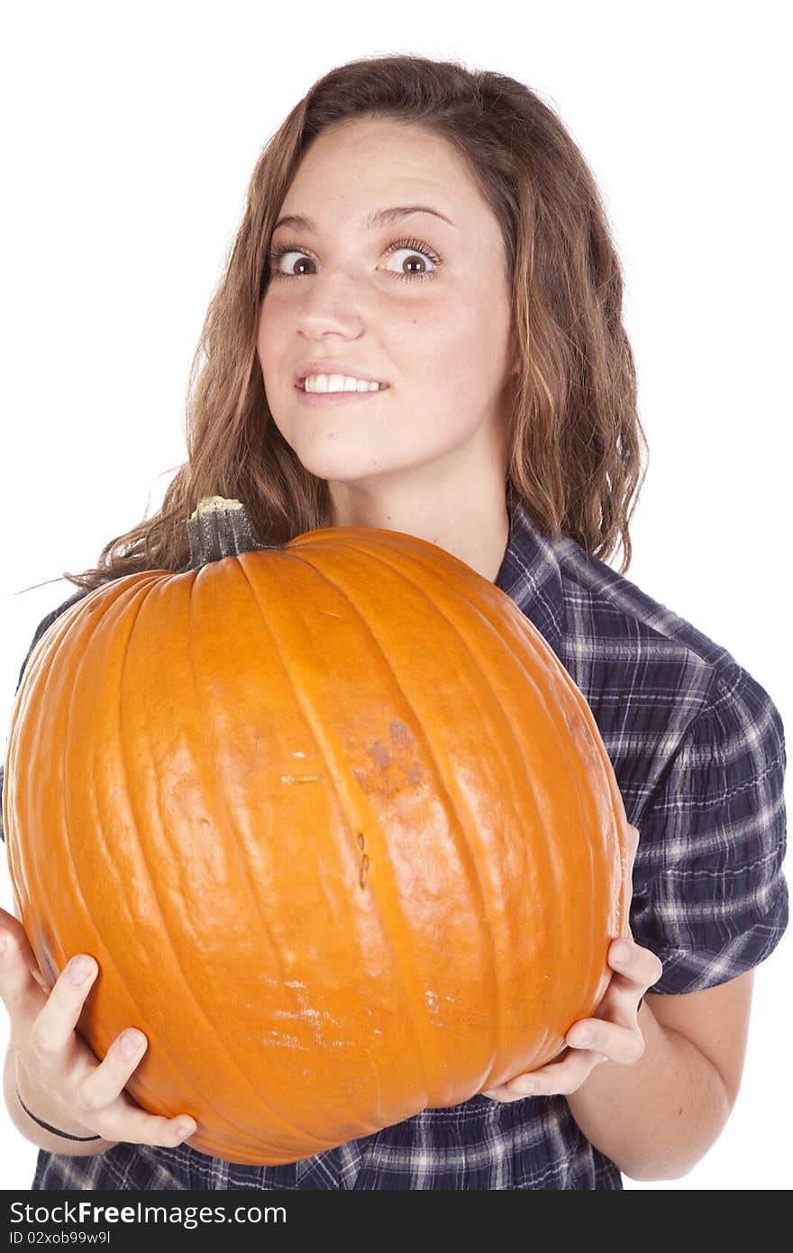 A woman in a blue shirt is holding a big pumpkin. A woman in a blue shirt is holding a big pumpkin.