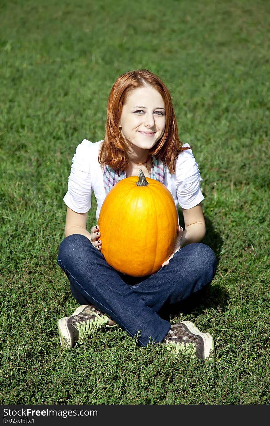 Women sitting at green grass and keeping pumpkin.