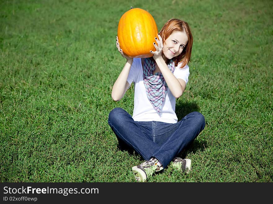 Women Sitting At Green Grass And Keeping Pumpkin.