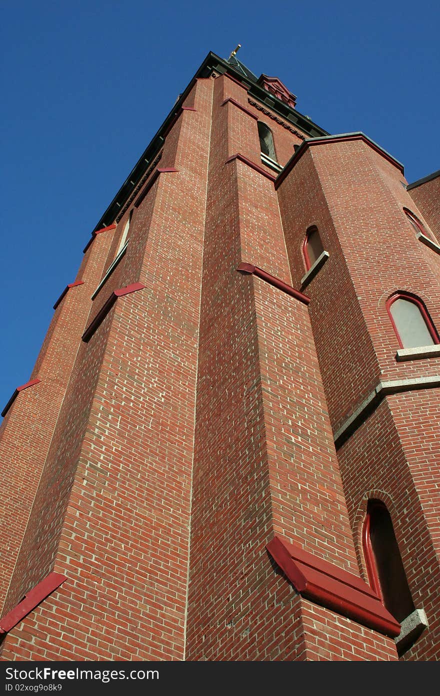 Towering brick church steeple against blue sky. Towering brick church steeple against blue sky