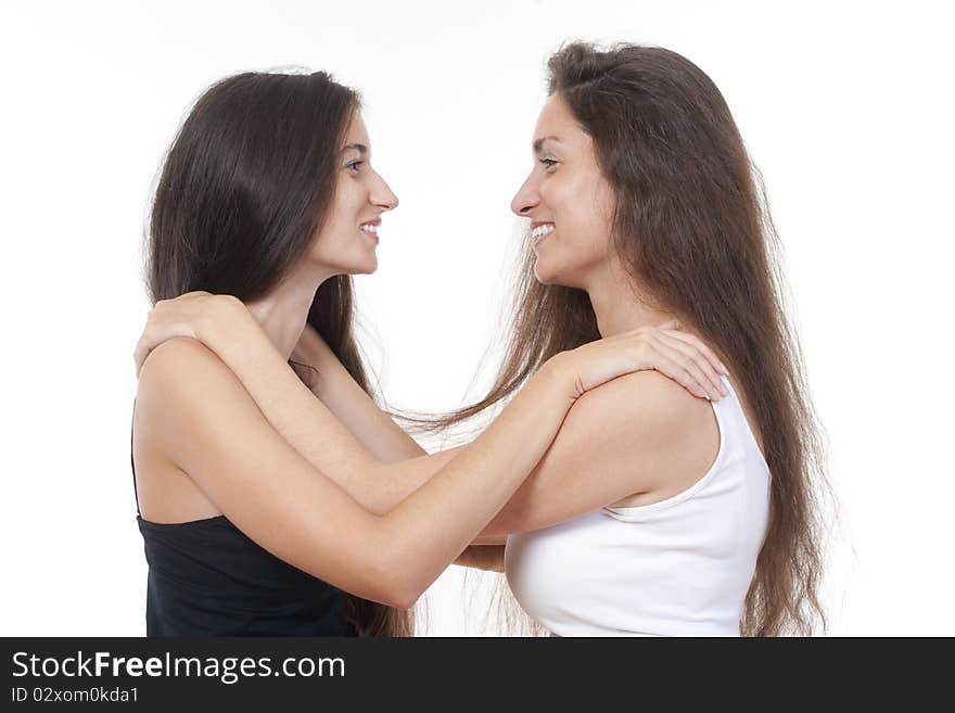 Two sisters with long brown hair embracing each other, smiling. Two sisters with long brown hair embracing each other, smiling