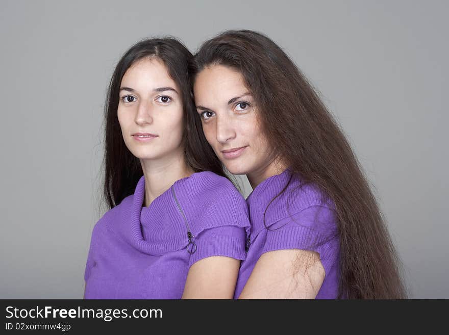 Portrait of two sisters with very long brown hair -isolated on gray