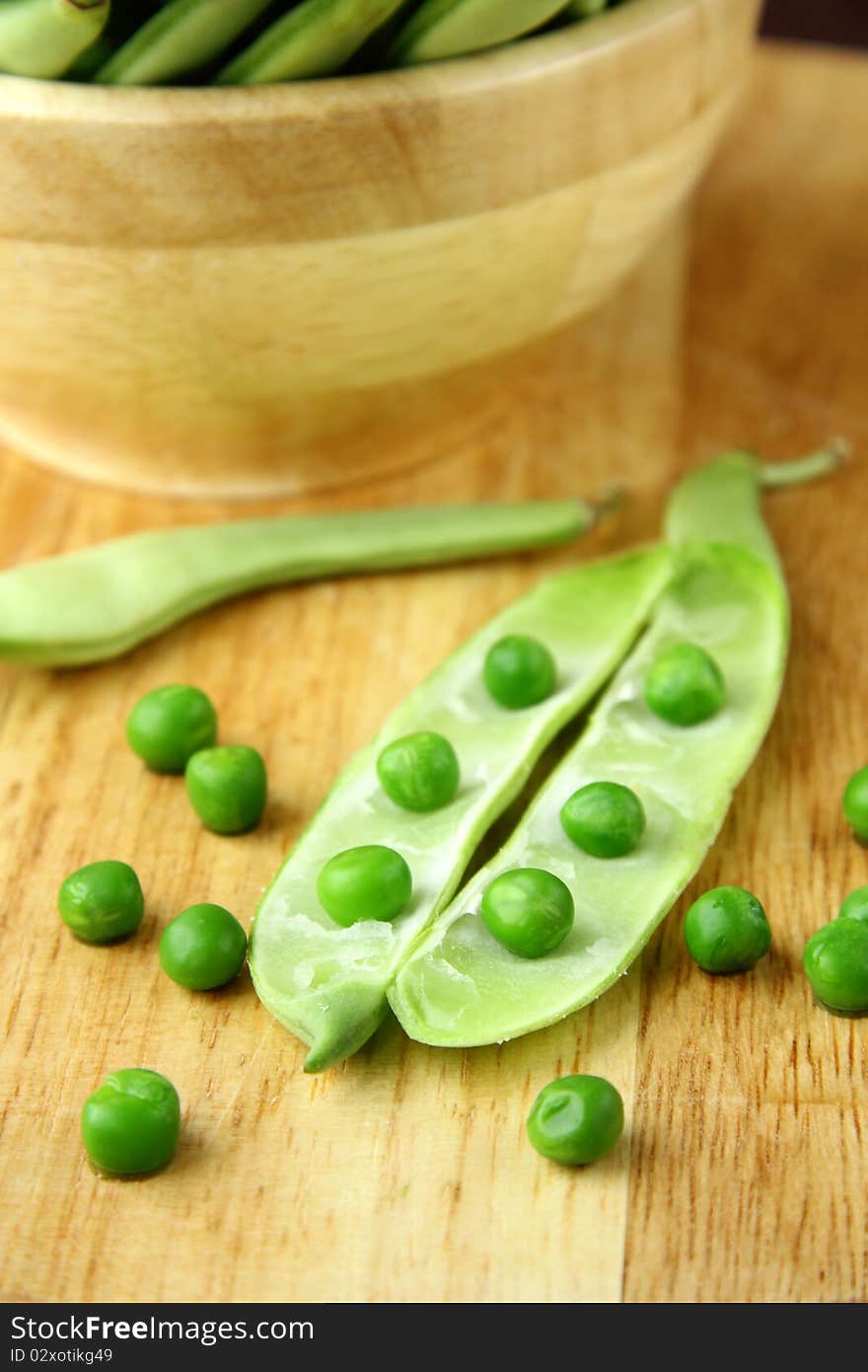 Green peas in a wooden bowl and on the board