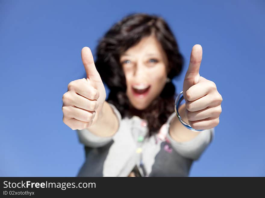 Portrait of beautiful brunette girl with blue eyes which show hand OK symbol.