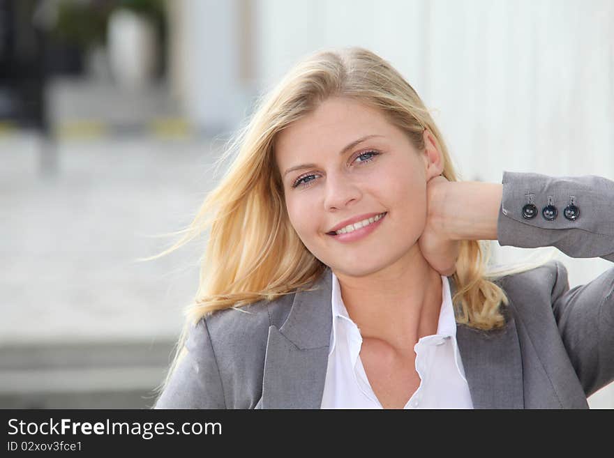 Blond businesswoman standing against a wall. Blond businesswoman standing against a wall