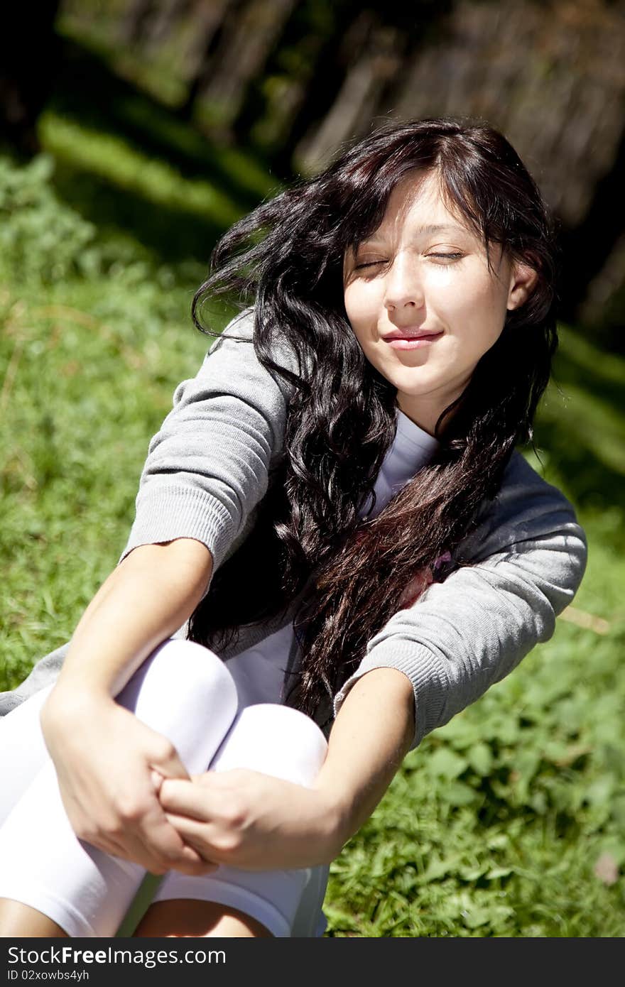 Brunette Girl On Green Grass In The Park.